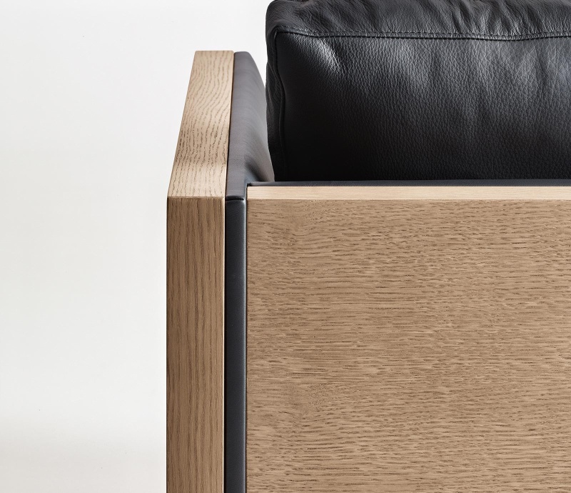 Détails du canapé Steeve d'Arper avec une structure extérieure en bois précomposé. Le piètement est en acier tubulaire gris anthracite le revêtement des coussins est en cuir noir.