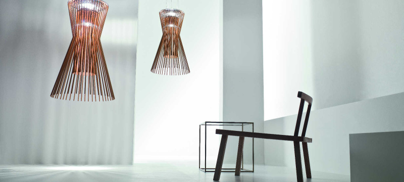 Suspensions Allegro Vivace de Foscarini disposée dans une pièce épurée aux ombrages gris. Ces dernières sont en aluminium verni et métal chromé et sont de couleur cuivre. Allegro Vivace est composé de lignes géométriques essentielles et habillé de reflets cuivrés.