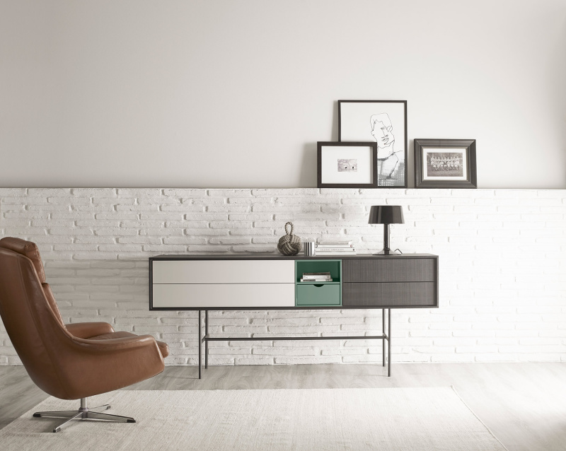 Buffet haut de rangement Aura de Treku disposé dans un salon. Les pieds du buffet sont en métal et la structure est composée d'un corps en mélaminé avec un placage en bois de chêne. Ce dernier est équipé de tiroirs et de placards battants.